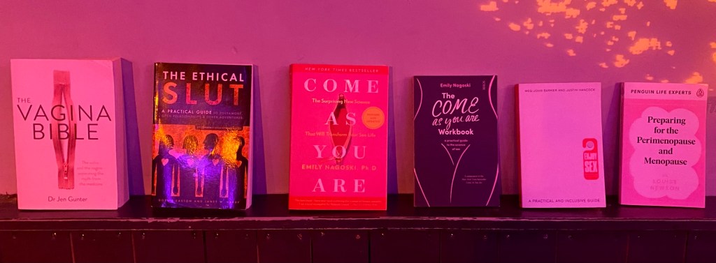 Books on pleasure, sex, relationships, ethical non-monogamy, pleasure, the vagina and vulva on display on a shelf